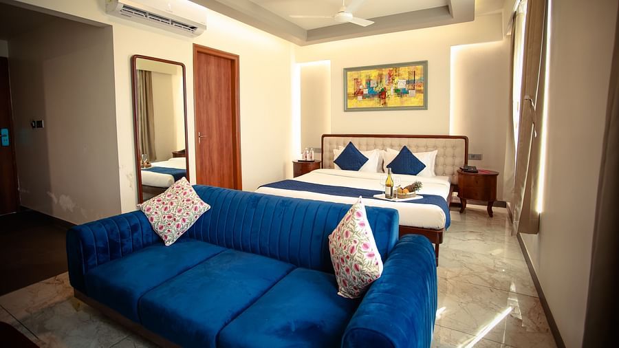 Deluxe King Room with a plush blue sofa, soft pillows, and warm lighting at Clarks Inn Suites Jaipur, Ajmer Road